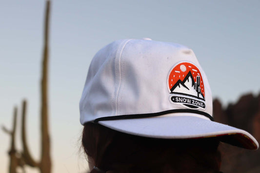 White hat with embroidered Snow Zone patch and black trim on visor
