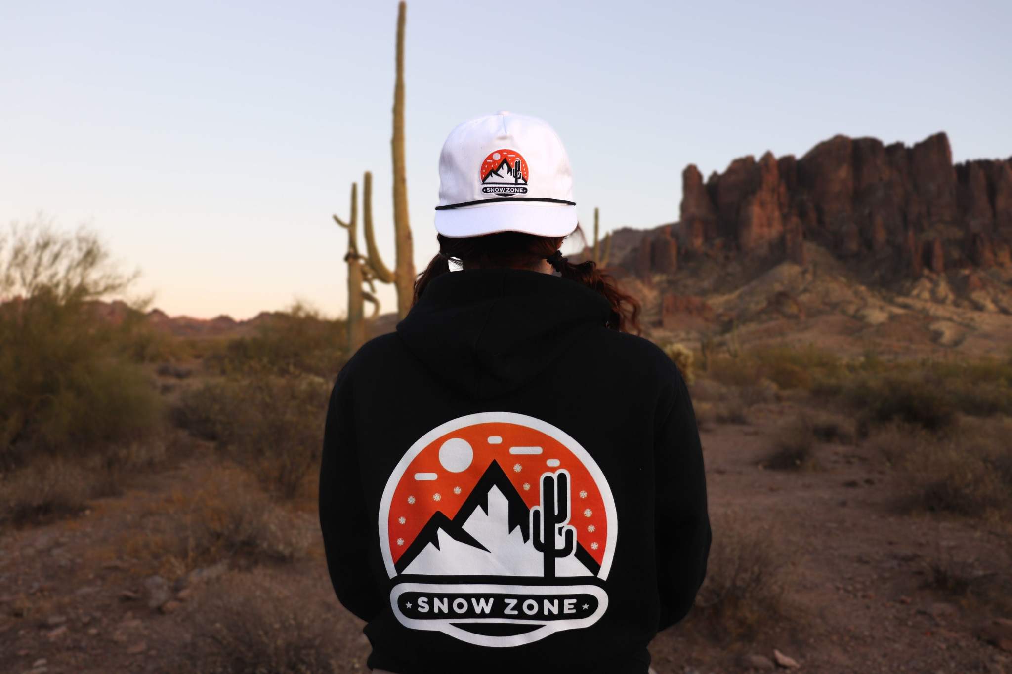 Black hoodie with Snow Zone graphic on the back worn outdoors in desert landscape