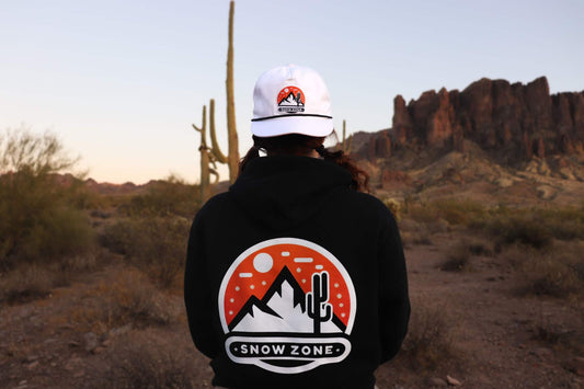 Black hoodie with Snow Zone graphic on the back worn outdoors in desert landscape